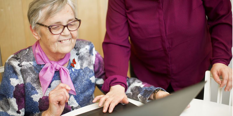 Iäkäs nainen tutkii avustajan kanssa muistiyhdistyksen nettisivuja kannettavalla tietokoneella. Kuvaaja Heidi-Mari Männistö.